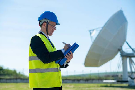 radome project manager in front of large satellite antenna